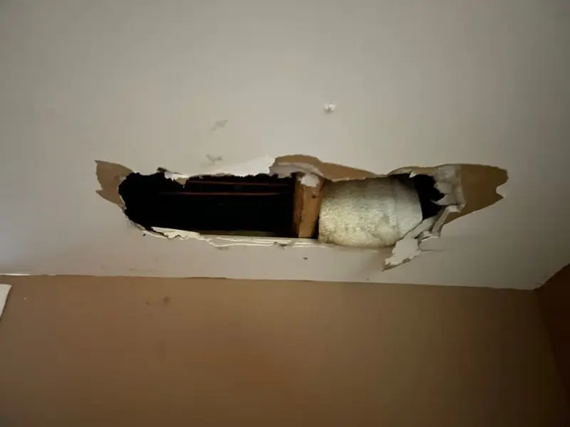 Hole broken through a wall above a doorway, Centereach, NY