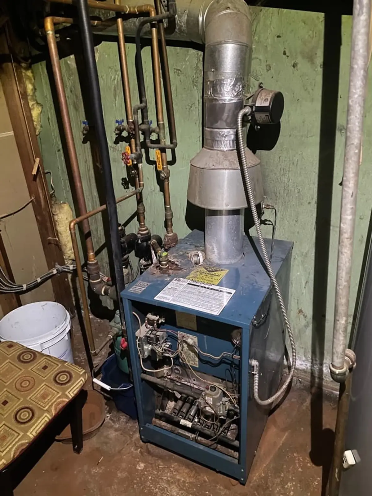 Selling a parent’s house after a move to care in Centereach: old boiler and piping in a utility room